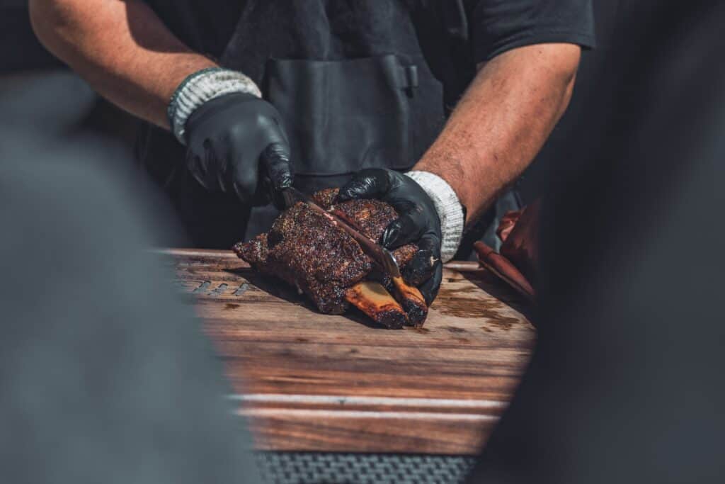 Chef carving smoked meat on a wooden board